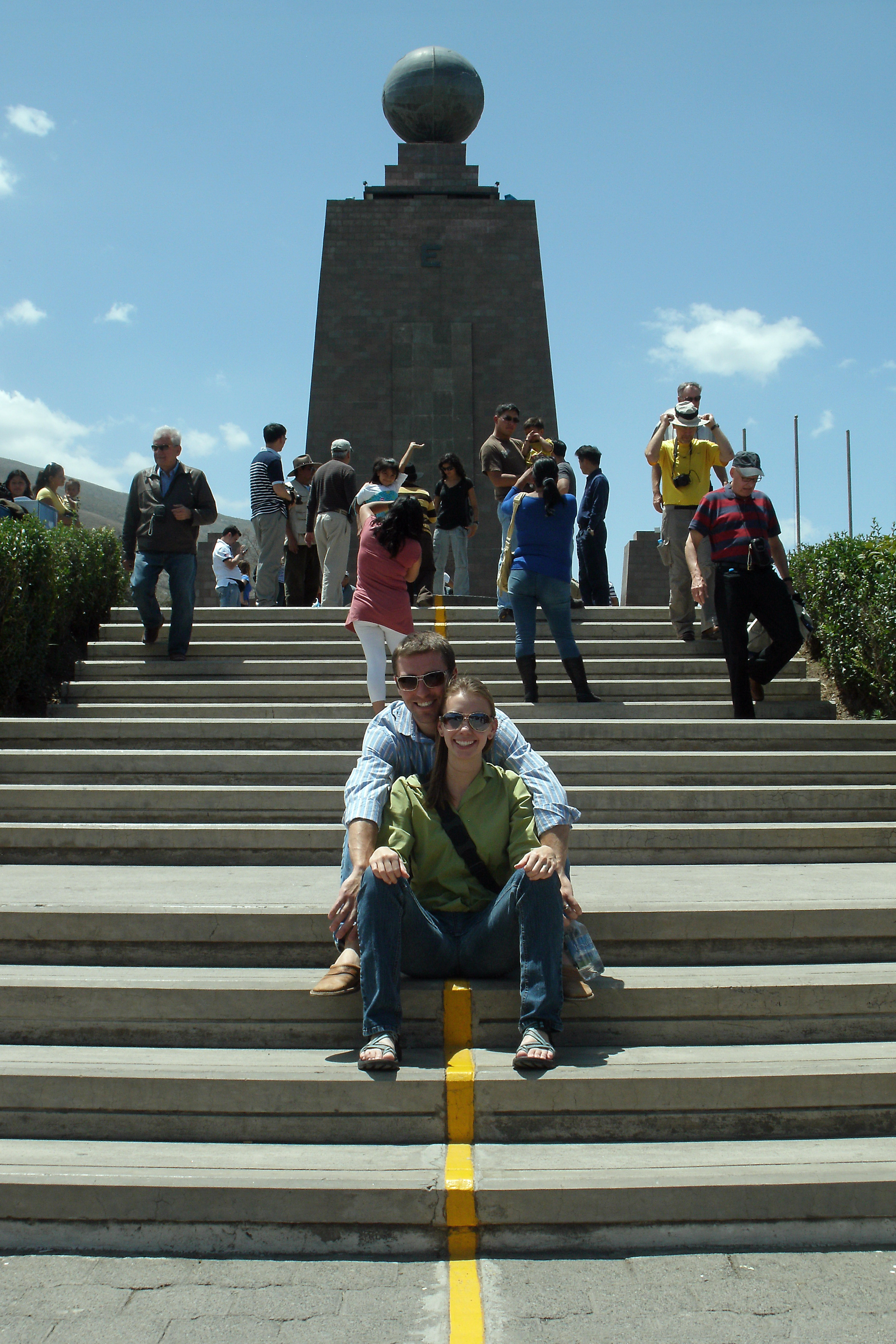 Couple Sitting on Equator at Middle of the World Monument in Ecuador